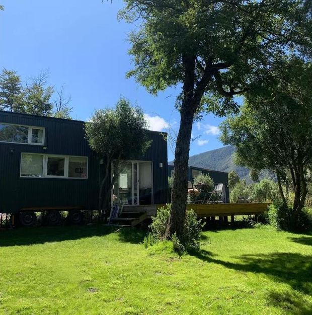 Tiny house junto a un árbol grande y el deck